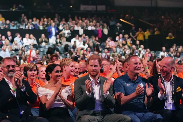 Dominic Reid and the Duke and Duchess of Sussex clap as they sit in the audience for an Invictus opening ceremony