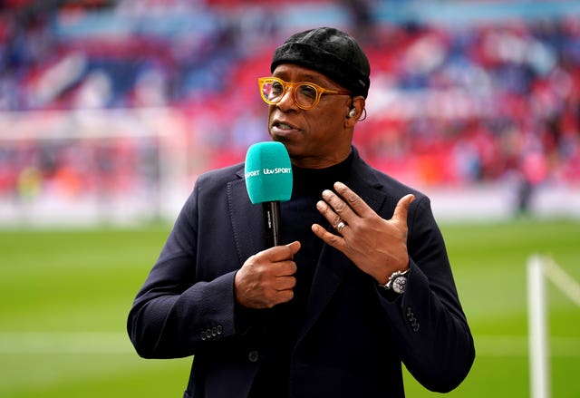 Ian Wright, holding a microphone, working as a pundit at a football match