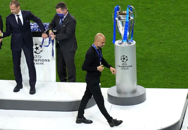 Manchester City manager Pep Guardiola with his runner-up medal as he walks past the Champions League trophy after the 2021 final