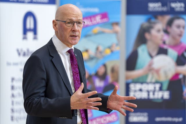 John Swinney gesturing with his arms while speaking