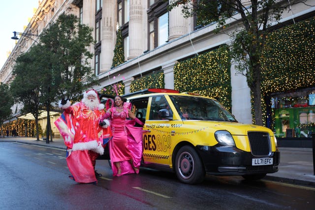 A man dressed as Santa with a woman in a pink gown exiting a taxi outside Selfridges