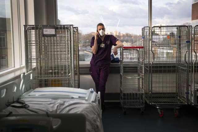 A consultant takes a moment to use his phone in the corridor of the ICU