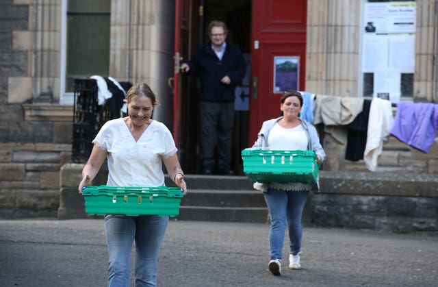 Volunteers from the Step to Hope charity carry meals to give to those who want one in the grounds of The Parish Church of St Cuthbert in Edinburgh