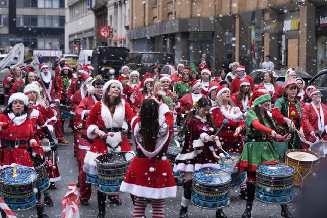 People in Santa suits play steel drums 