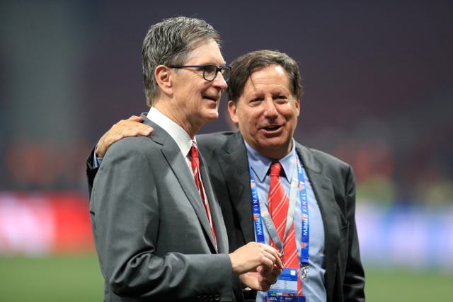 Fenway Sports Group's principal owner John W Henry and Liverpool chairman Tom Werner embrace on the pitch