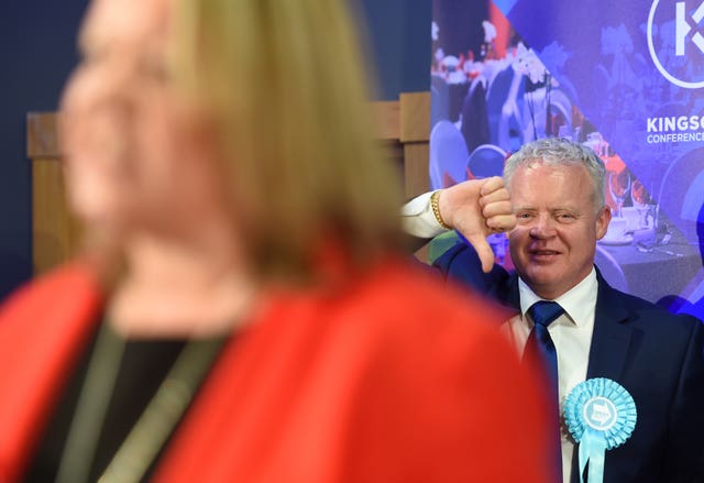 Brexit Party candidate Mike Greene gives a thumbs down as Ms Forbes gives her winners speech