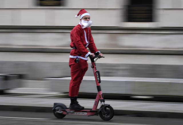 A Santa riding an electric scooter