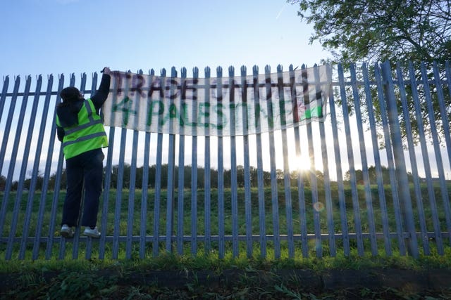 A protester hangs a banner on a fence outside weapons manufacturer BAE Systems in Rochester, Kent