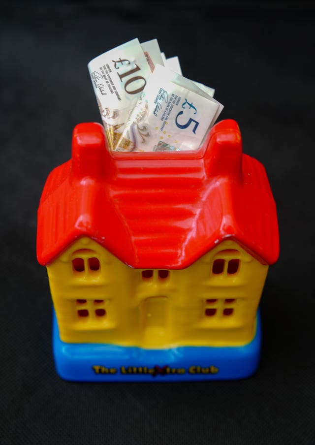A money box shaped like a house filled with bank notes