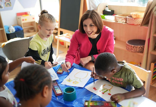 Bridget Phillipson paints pictures of flowers with four children in a school classroom