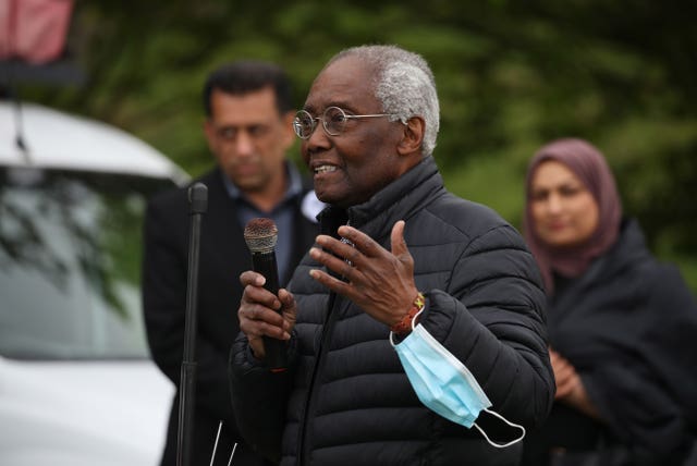 Sir Geoff Palmer gesturing with one hand as he speaks into a microphone at a rally