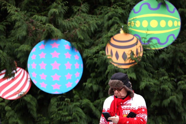 A man checks the odds in front of a tree festooned with giant decorations 