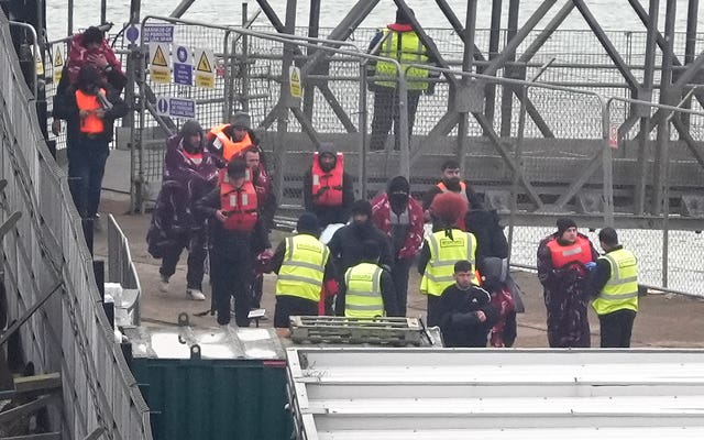 People, some wearing life jackets, disembarking a vessel