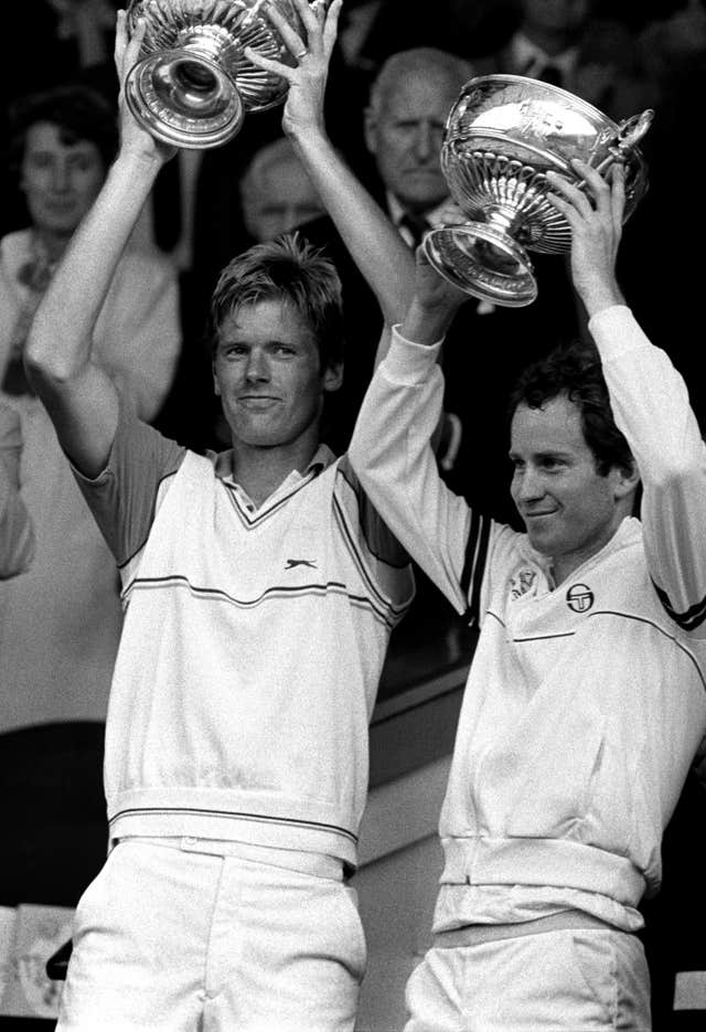 John McEnroe, right, and Peter Fleming lift the men's doubles trophies at Wimbledon 