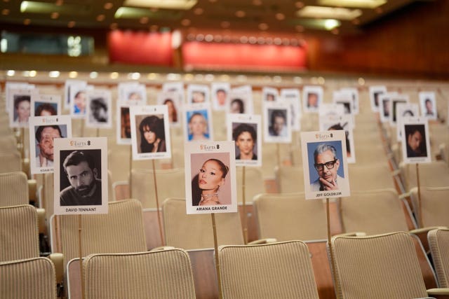 Pictures of heads on sticks are arranged on chairs