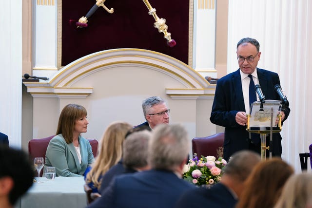 Rachel Reeves seated while Andrew Bailey delivers a speech