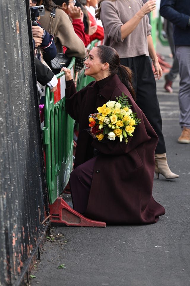 Meghan crouches down to meet a youngster 