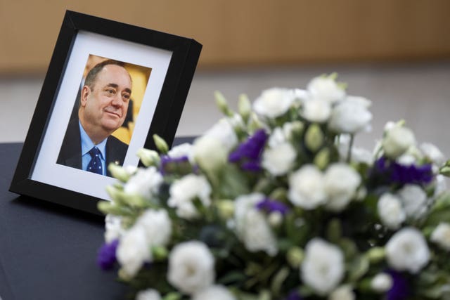 A photograph of Alex Salmond and flowers alongside a book of condolence in his memory, at The Scottish Parliament in Edinburgh.