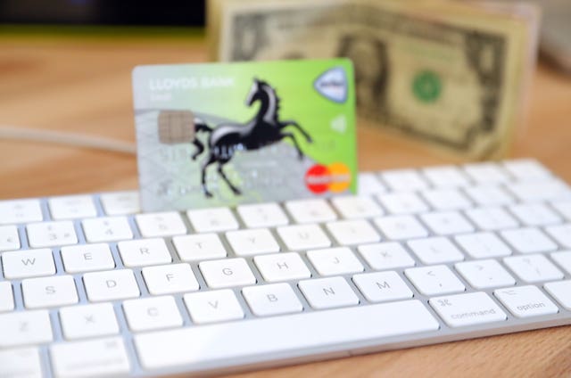 A Mastercard stands on a keyboard next to a computer