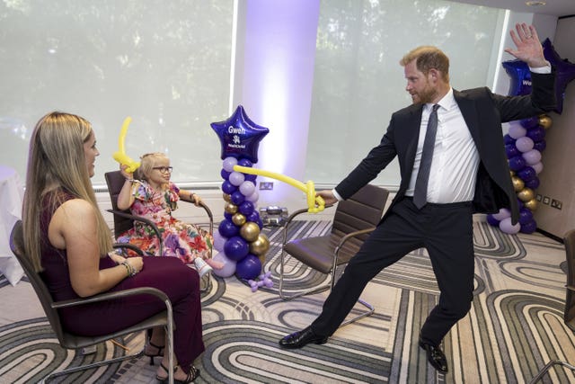 Harry play fights using swords made from modelling balloons with nine-year-old Gwen Foster at the annual WellChild Awards 2025 