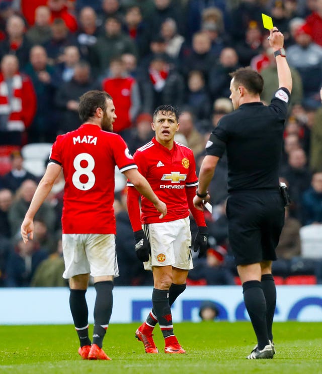 United’s Alexis Sanchez, centre, is shown a yellow card
