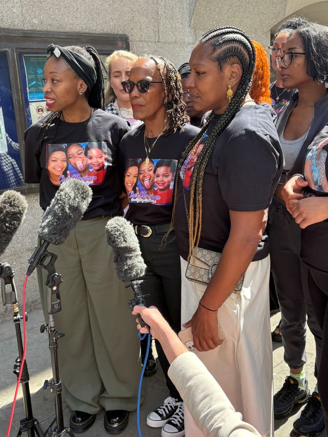 Three women speaking in front of microphones, each wearing a T-shirt featuring photos of Cher Maximen