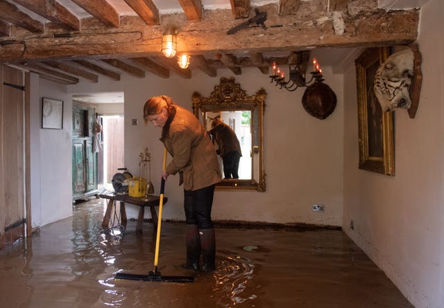 Local resident Roz attempts a clean-up operation in Cossington, as floodwaters cover the ground floor in her home 