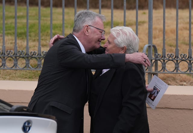 Mike Nesbitt (left) and John Linehan embrace outside the church