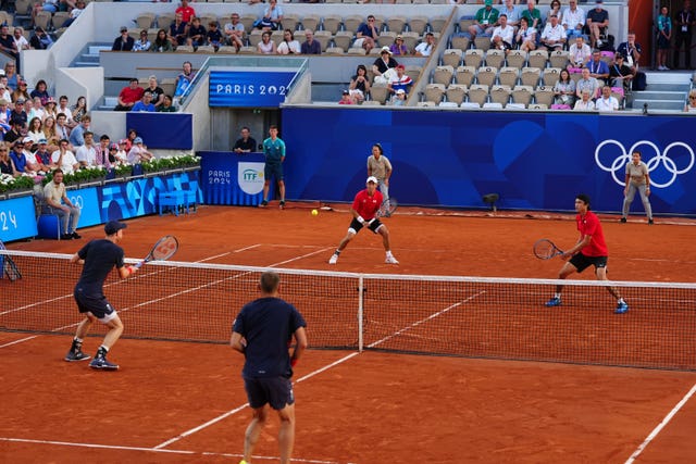 Andy Murray, left, hits a volley as his doubles partner Dan Evans watches on.