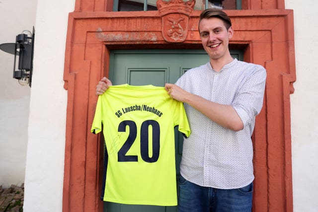 Local comedian Jonas Greiner holds up a SG Lauscha/Neuhaus shirt which England’s Harry Kane signed