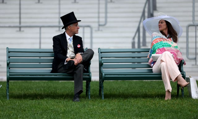 Racegoers chat whilst sitting on a bench during day five of Royal Ascot (Steven Paston/PA)