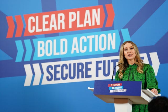 Laura Trott speaking behind a lectern in front of the Conservatives' General Election slogan of 'Clear Plan, Bold Action, Secure Future'