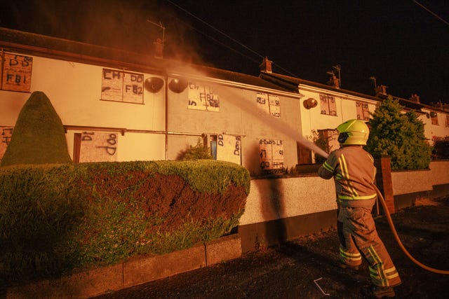 A firefighter hoses down properties close to the Craigyhill eleventh night bonfire in Larne