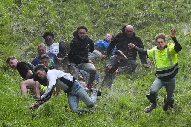 Participants risk life and limb as they race down the very steep Cooper's Hill in Gloucestershire after an 8lb Double Gloucester cheese (Jacob King/PA)