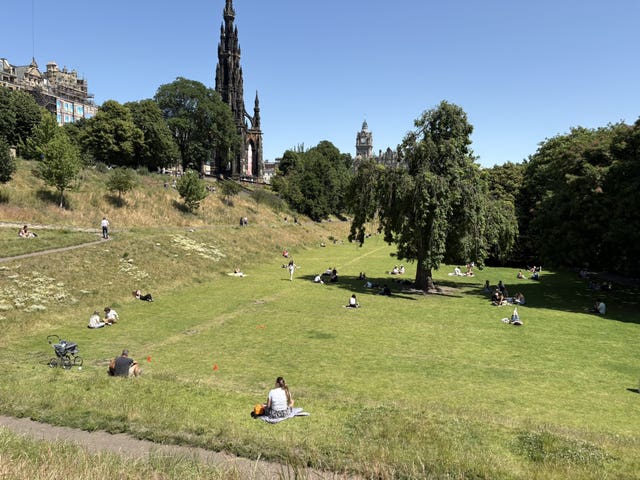 People enjoy the hot weather on a grassy area