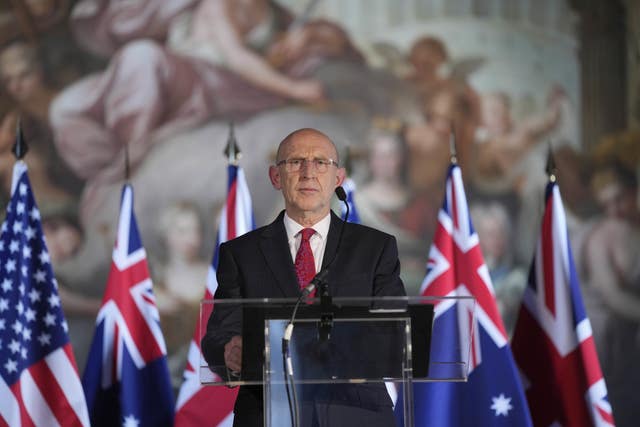 Defence Secretary John Healey speaking during a press conference with UK, US and Australian flags in the background