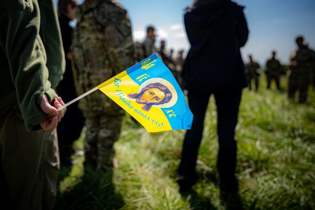 A small Ukrainian flag being held by one of several soldiers in a field