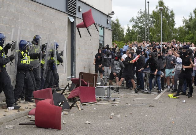 A chair is launched at police officers as a group of people gathers outside a hotel