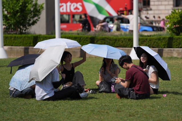 People in the sun in Parliament Square, London