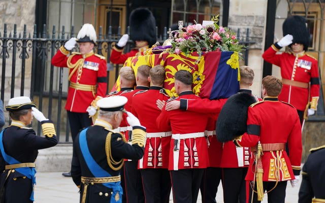 King Charles III and the Princess Royal salute their mother's coffin as it is carried into Westminster Abbey