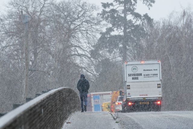 A pedestrian crosses a bridge during a snow shower near Maidstone in Kent