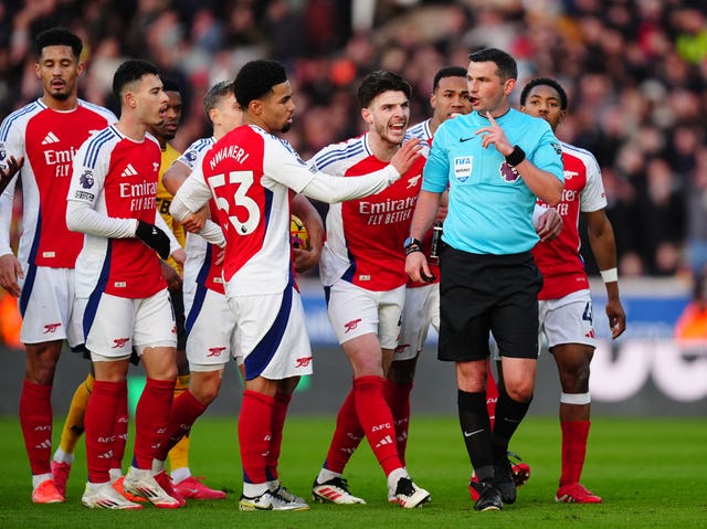 Referee Michael Oliver is surrounded by Arsenal players after the  dismissal of Myles Lewis-Skelly