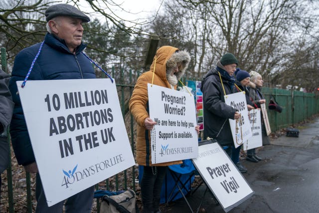 Four people forming a protest, holding placards which are against abortion