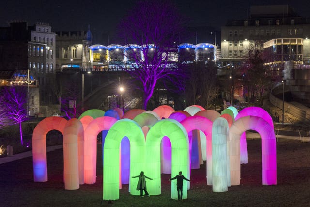 Two people explore giant illuminated arches