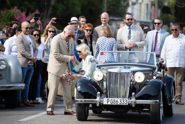 The Prince of Wales helps the Duchess of Cornwall out of an MG TD sports car from 1953 as they arrive at a British classic car event in Havana, Cuba