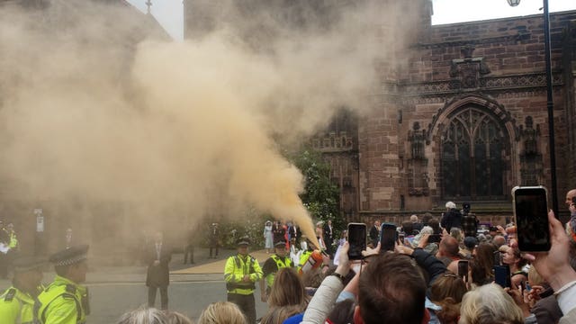 Orange smoke rises over the crowd watching the wedding of Hugh Grosvenor, the Duke of Westminster, and Olivia Henson outside Chester Cathedral