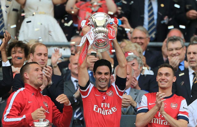 Arsenal players Lukas Podolski, Mikel Arteta and Thomas Vermaelen lift the FA Cup