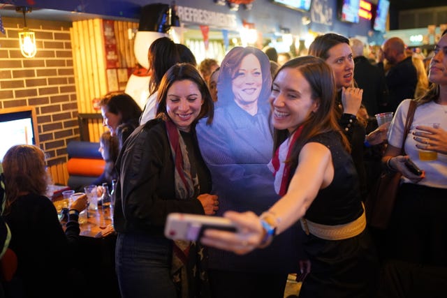 People pose for photos with a cardboard cutout of Kamala Harris at the Democrats Abroad US election watching event in central London