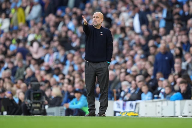 Manchester City boss Pep Guardiola points with his right hand on the touchline