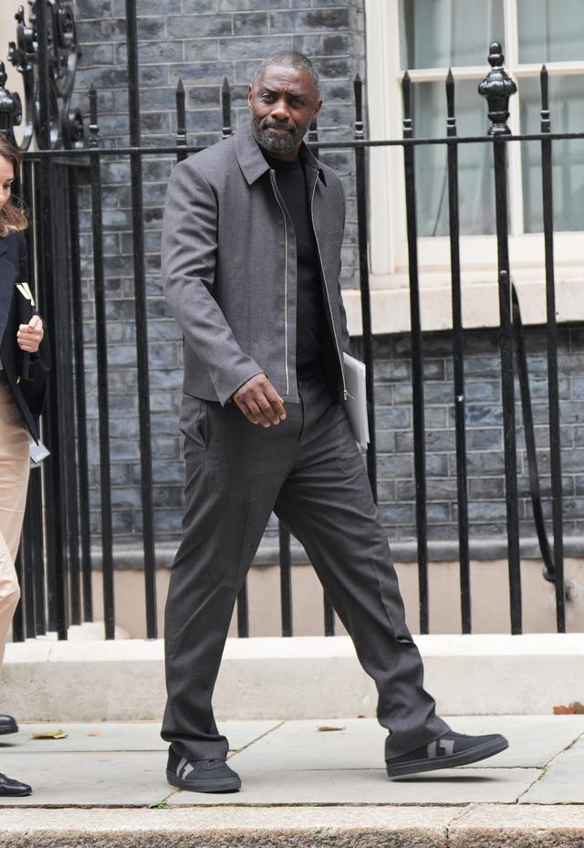 Actor Idris Elba, wearing a grey jacket, black jumper, grey trousers and black trainers, walks past black railings as he leaves 10 Downing Street after a knife crime summit